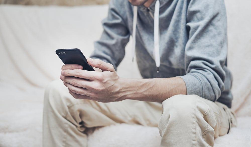 Homem sentado mexendo no celular